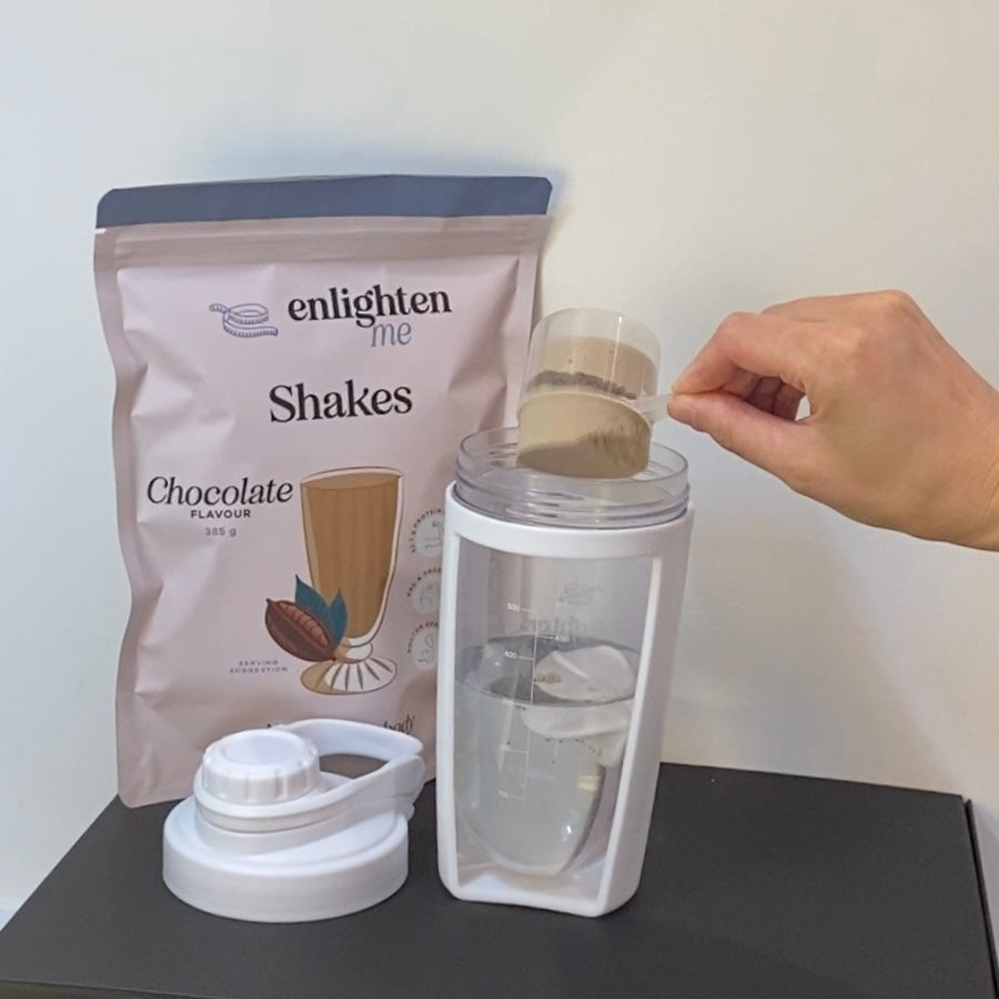 A demonstration picture of the Enlighten Me Shake in Chocolate Flavour, a high protein meal replacement shake, being measured with a scoop and poured into the Enlighten Me Shaker. 