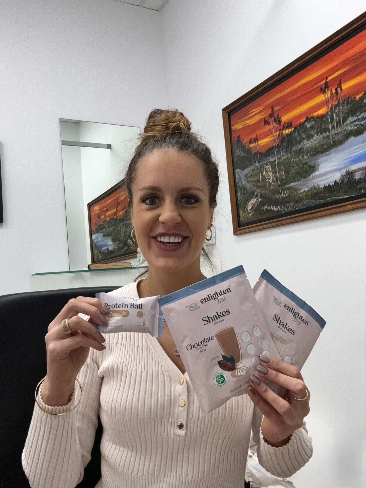 Dr India Latimore enjoying an Enlighten Me Protein Ball with the Enlighten Me Chocolate and Vanilla Shakes.