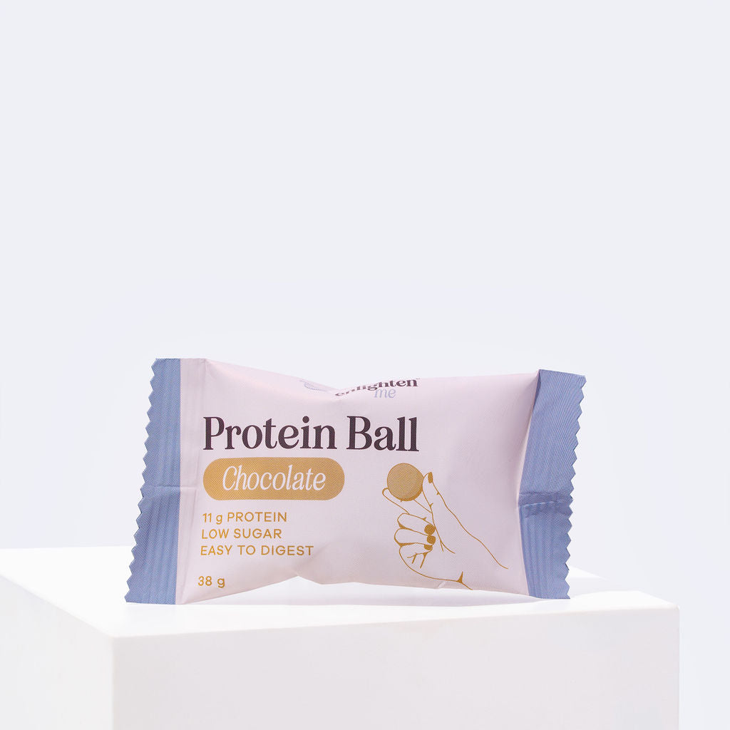 Front of an individually wrapped Enlighten Me Chocolate Protein Ball, 38g with 11g protein, low sugar and easy to digest, in a blush and blue wrapper.