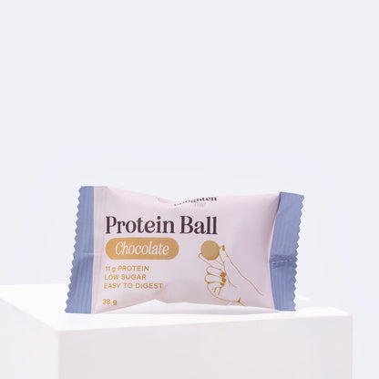 Front of an individually wrapped Enlighten Me Chocolate Protein Ball, 38g with 11g protein, low sugar and easy to digest, in a blush and blue wrapper.