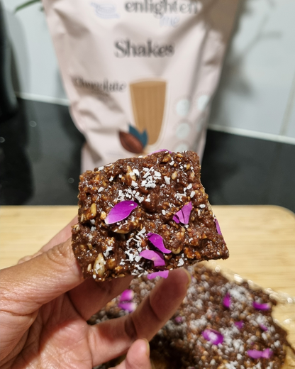 Hand holding a chocolate brownie with Enlighten Me Shakes in Chocolate flavour
